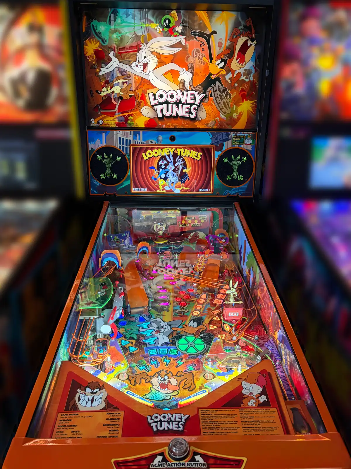 A vertical view of a colorful Looney Tunes pinball machine with a dynamic backglass and illuminated playfield, featuring Bugs Bunny and the Tasmanian Devil.