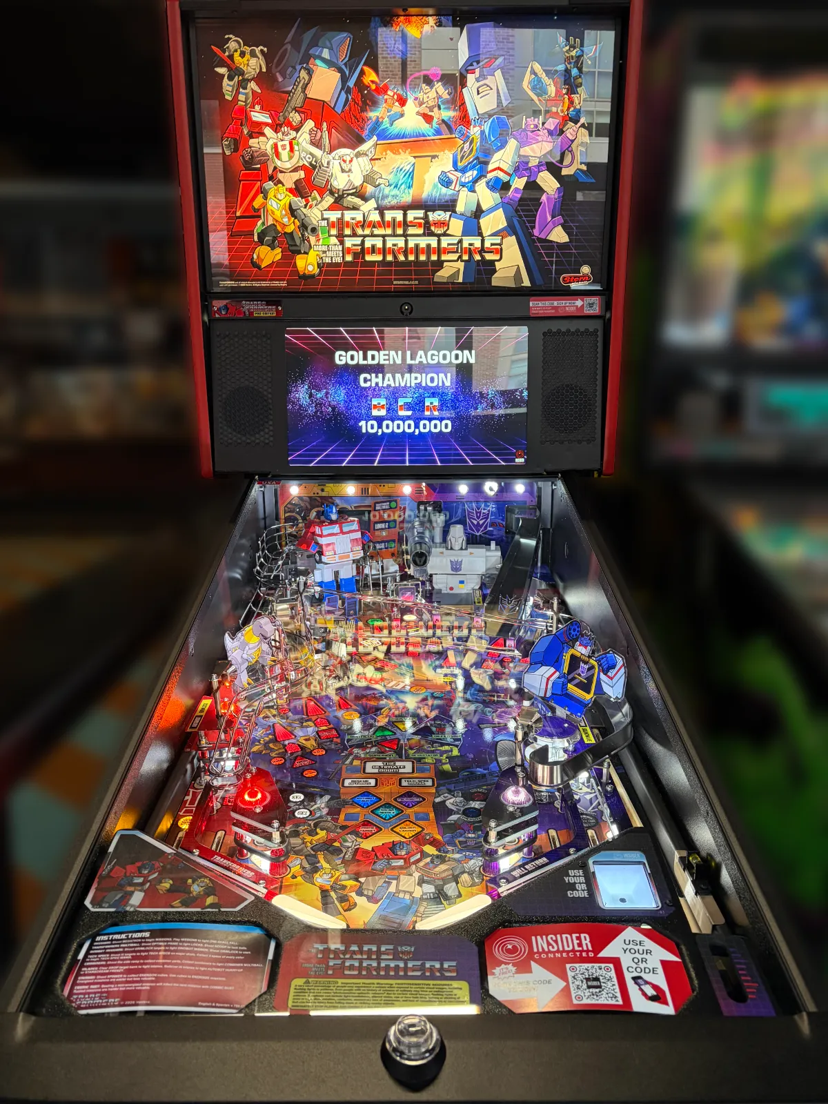 A Stern Transformers pinball machine is powered on, displaying the playfield, backglass art, and a high score of 10,000,000 points.